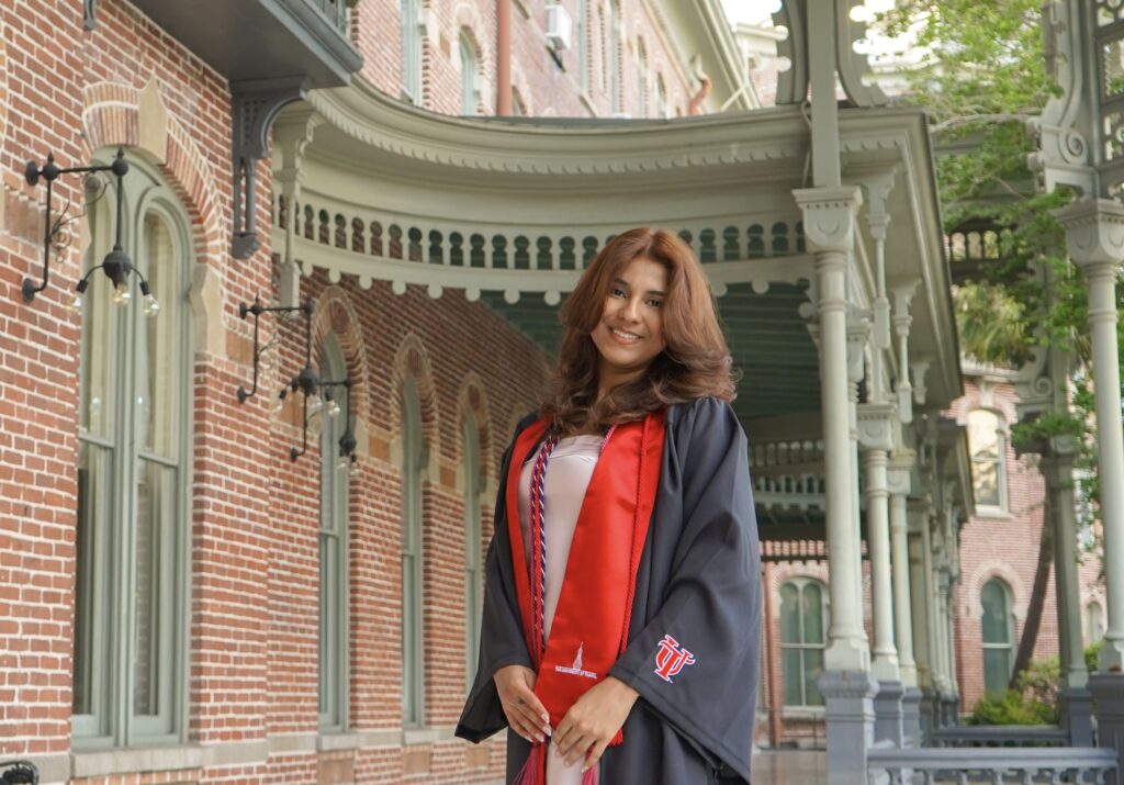 woman wearing graduation robe standing by beautiful buildings