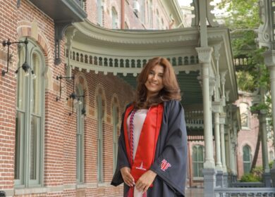 woman wearing graduation robe standing by beautiful buildings