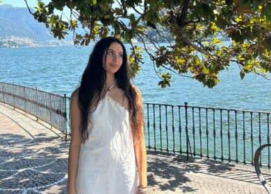 Woman in white dress standing by tree and blue water