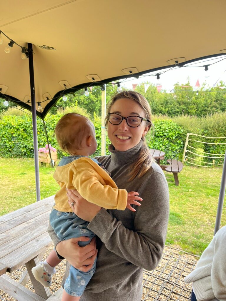 Woman in gray turtleneck holding young child.