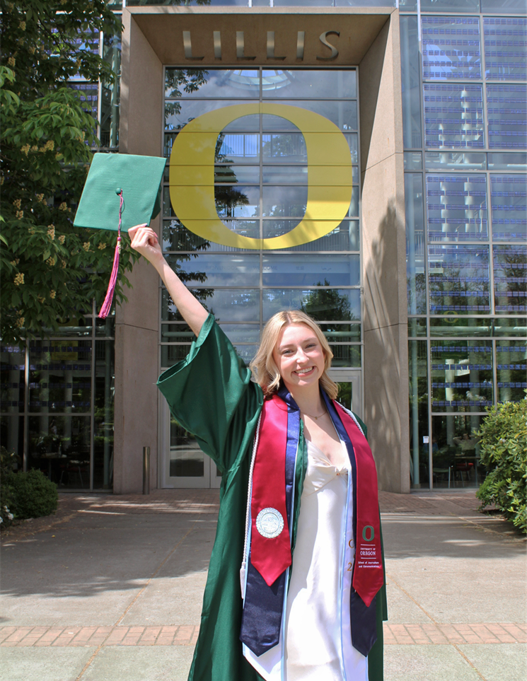 Woman on University of Oregon campus in graduation gown and cap