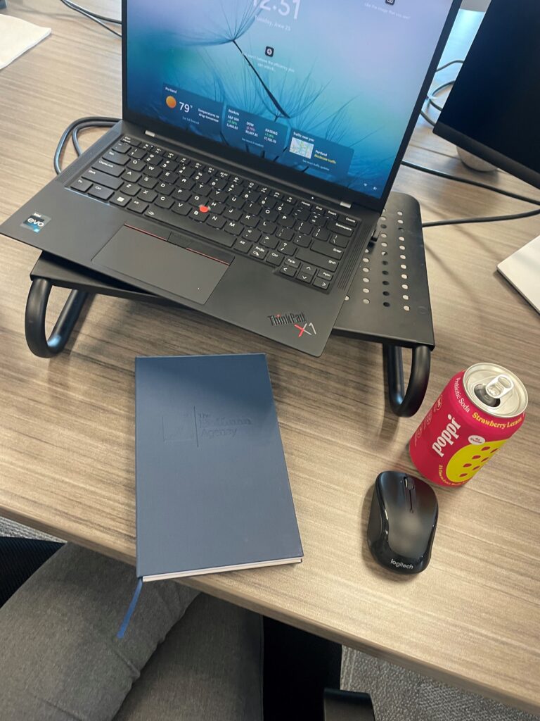 Desk setup with a laptop, mouse and notebook