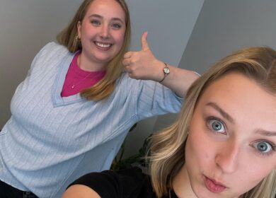 Two women cheerfully posing in an office